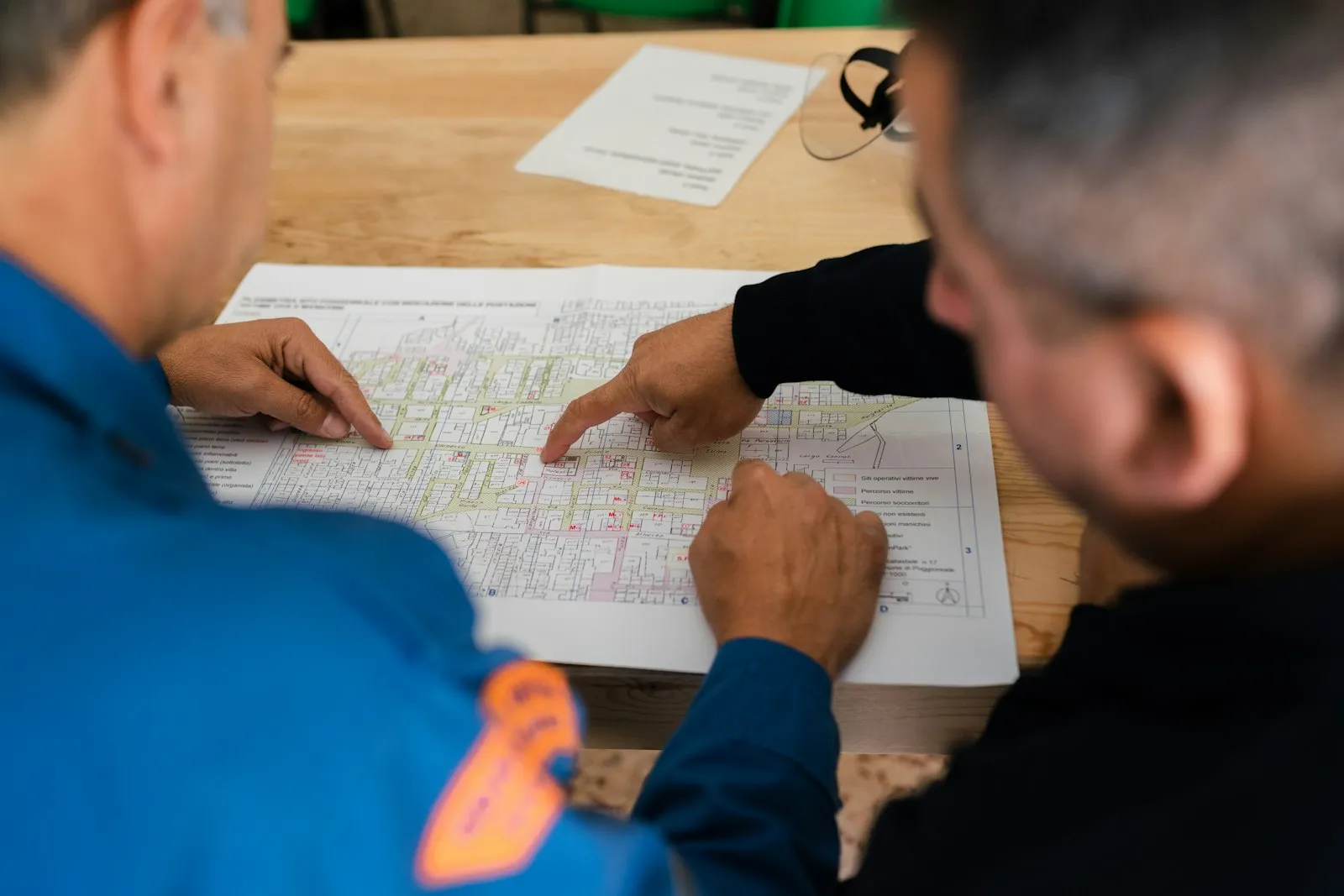 Dois profissionais analisando a planta da obra sobre a mesa